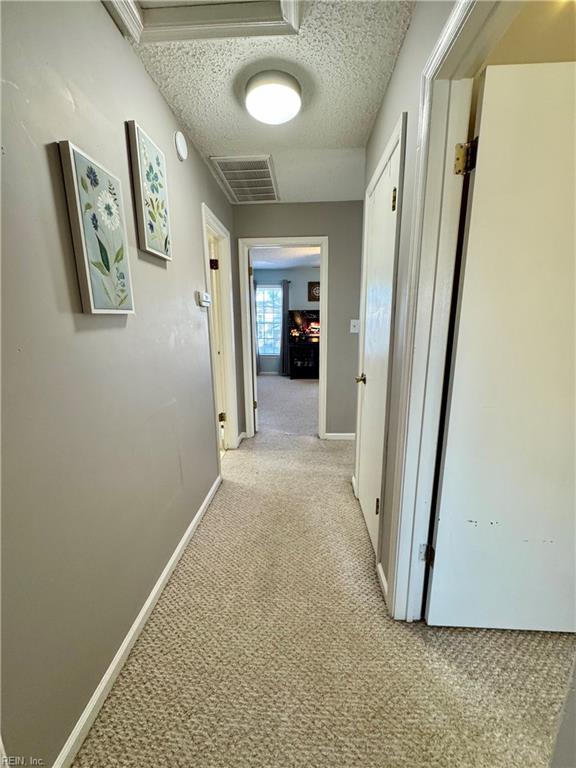 hall with light carpet and a textured ceiling