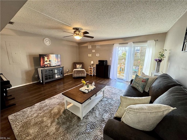 living room with dark hardwood / wood-style flooring, ceiling fan, and a textured ceiling