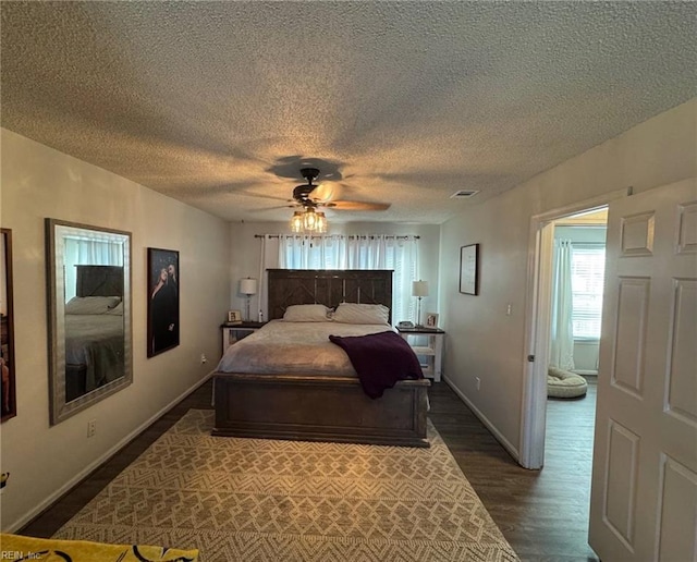 bedroom with a textured ceiling, dark hardwood / wood-style floors, and ceiling fan