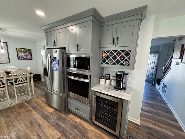 kitchen with dark wood-type flooring, stainless steel appliances, beverage cooler, and gray cabinetry