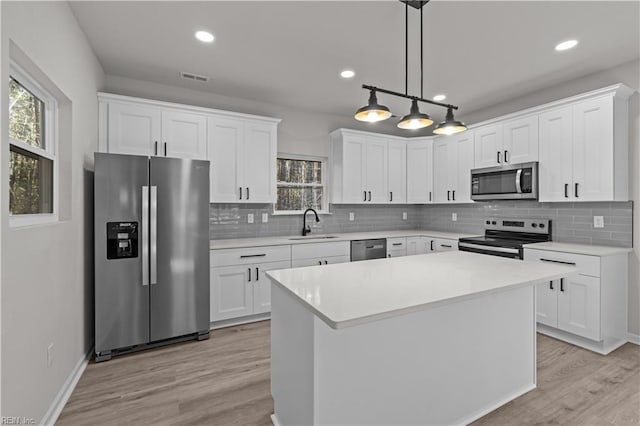 kitchen featuring white cabinetry, sink, hanging light fixtures, a center island, and stainless steel appliances