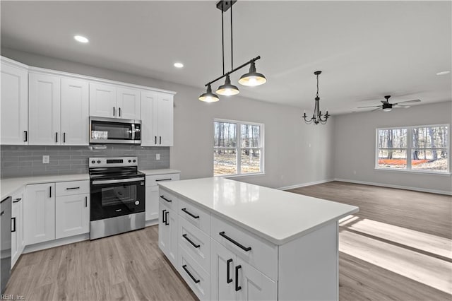 kitchen featuring pendant lighting, white cabinetry, stainless steel appliances, tasteful backsplash, and a kitchen island