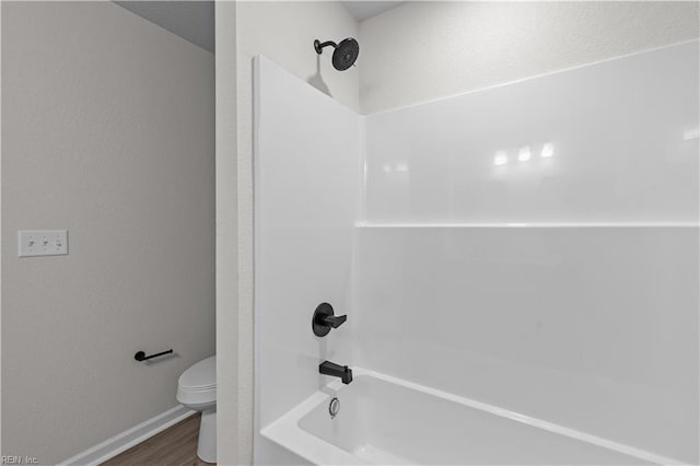 bathroom featuring wood-type flooring, shower / bathtub combination, and toilet