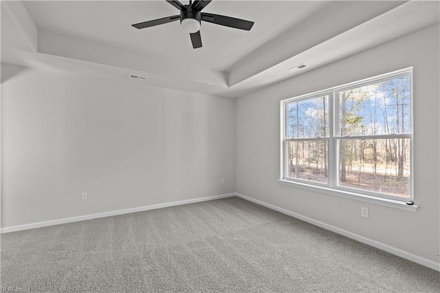 empty room featuring ceiling fan, carpet flooring, and a tray ceiling