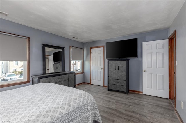 bedroom with multiple windows and hardwood / wood-style flooring