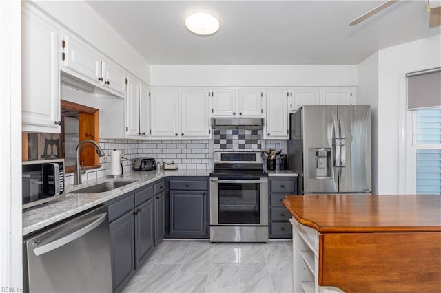 kitchen with sink, gray cabinets, appliances with stainless steel finishes, light stone counters, and white cabinets