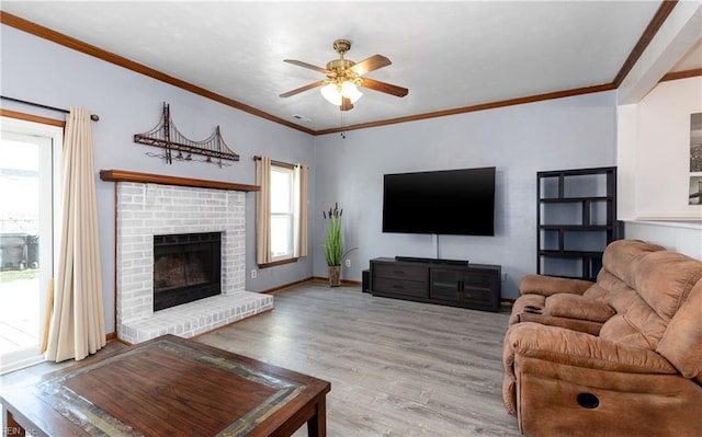 living room with ceiling fan, ornamental molding, a brick fireplace, and light hardwood / wood-style flooring