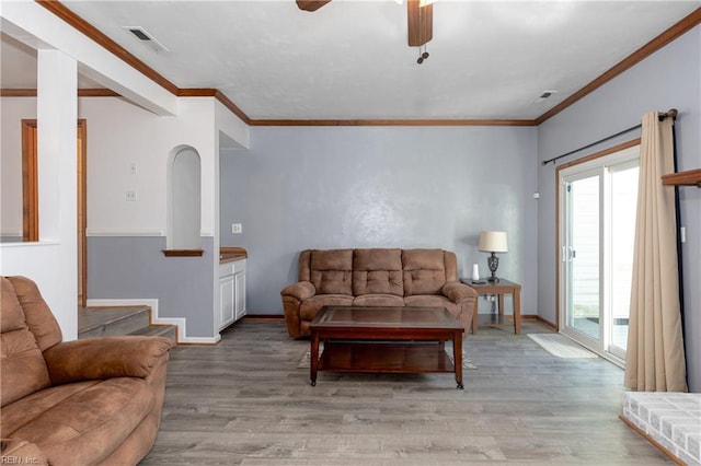 living room with crown molding, ceiling fan, and light wood-type flooring