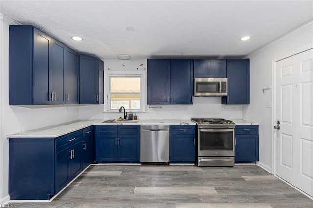 kitchen featuring stainless steel appliances, sink, blue cabinets, and light hardwood / wood-style flooring