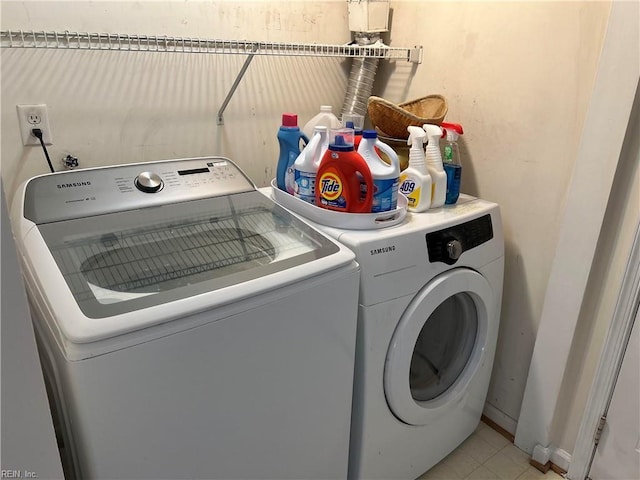 clothes washing area featuring light tile patterned floors and washing machine and clothes dryer