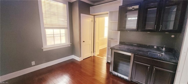 kitchen with wine cooler, sink, dark wood-type flooring, and dark stone counters