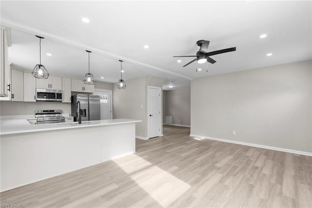 kitchen featuring sink, ceiling fan, stainless steel appliances, decorative light fixtures, and light wood-type flooring