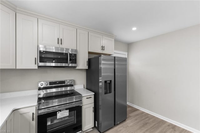 kitchen with stainless steel appliances, white cabinets, and light hardwood / wood-style floors