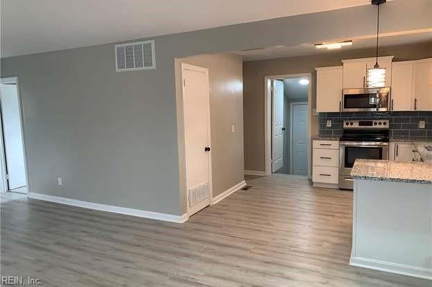 kitchen featuring appliances with stainless steel finishes, white cabinets, backsplash, hanging light fixtures, and light hardwood / wood-style flooring