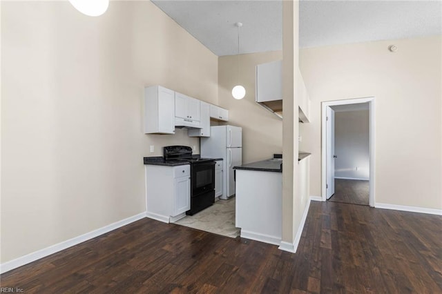 kitchen featuring high vaulted ceiling, dark hardwood / wood-style floors, white fridge, black range with electric stovetop, and white cabinets