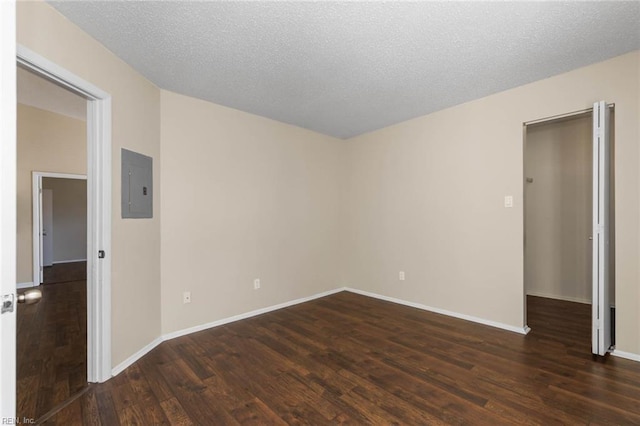 unfurnished room featuring dark hardwood / wood-style flooring, electric panel, and a textured ceiling