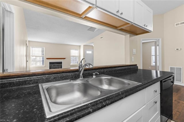 kitchen featuring sink, dishwasher, white cabinets, dark hardwood / wood-style flooring, and dark stone counters