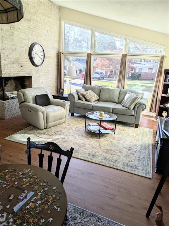 living room with brick wall, a fireplace, and hardwood / wood-style floors