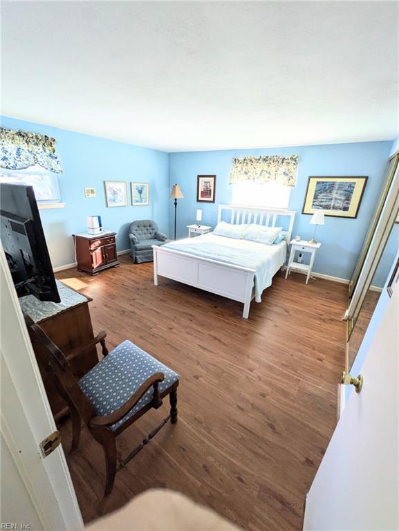 bedroom featuring multiple windows and dark hardwood / wood-style flooring