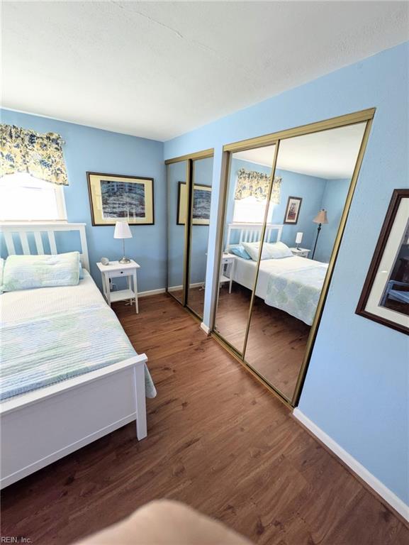 bedroom with multiple windows, two closets, and dark hardwood / wood-style flooring