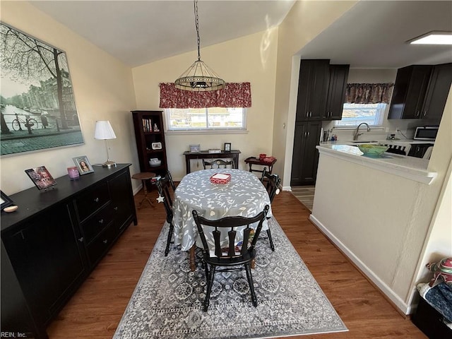 dining space featuring sink, hardwood / wood-style flooring, and vaulted ceiling