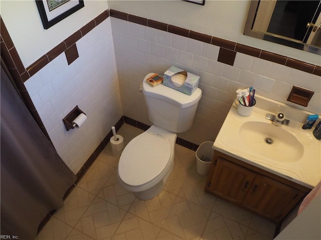 bathroom with vanity, toilet, and tile walls