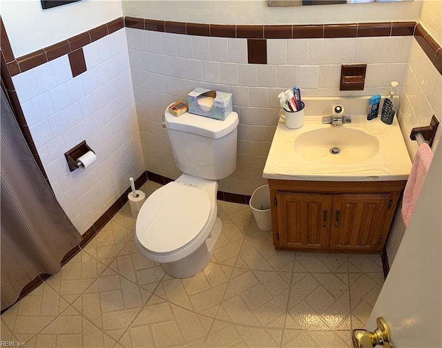 bathroom with tile patterned flooring, vanity, tile walls, and toilet