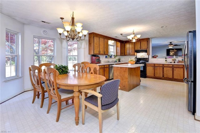 dining room with ceiling fan with notable chandelier and a textured ceiling