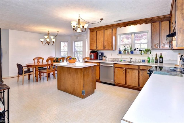 kitchen with a kitchen island, decorative light fixtures, sink, a chandelier, and stainless steel dishwasher