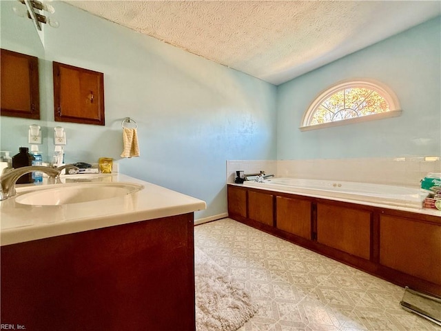 bathroom with vanity, a textured ceiling, and a tub