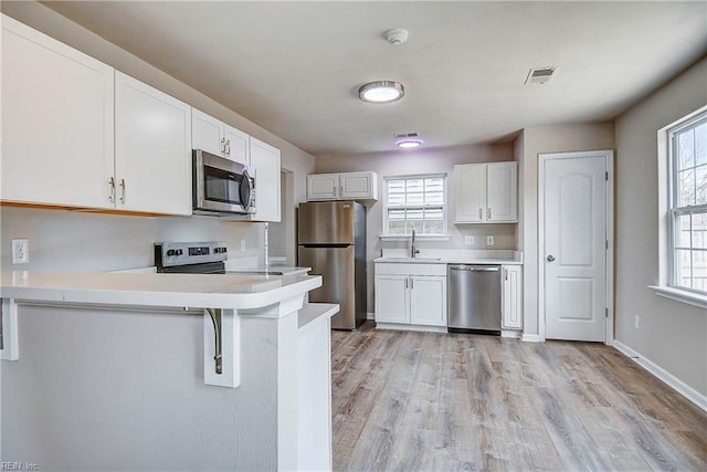 kitchen with stainless steel appliances, white cabinetry, sink, and a breakfast bar area