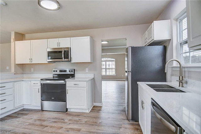 kitchen featuring stainless steel appliances, white cabinetry, sink, and light wood-type flooring