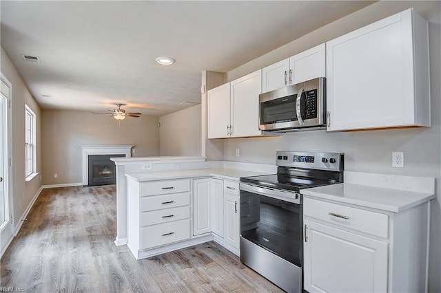 kitchen with white cabinetry, appliances with stainless steel finishes, light wood-type flooring, and kitchen peninsula