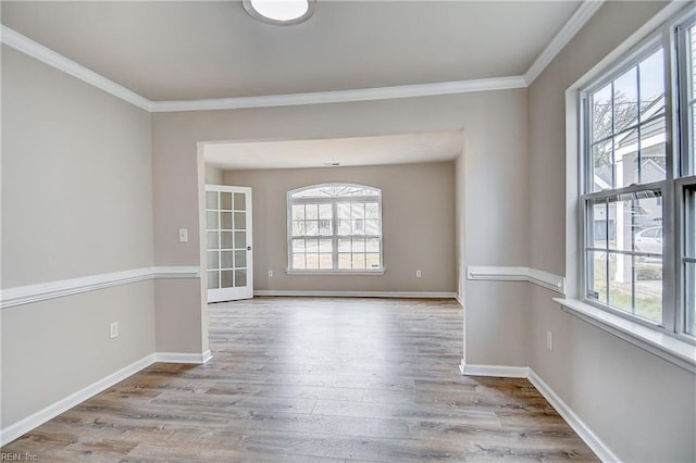 unfurnished room with ornamental molding, plenty of natural light, and light hardwood / wood-style flooring