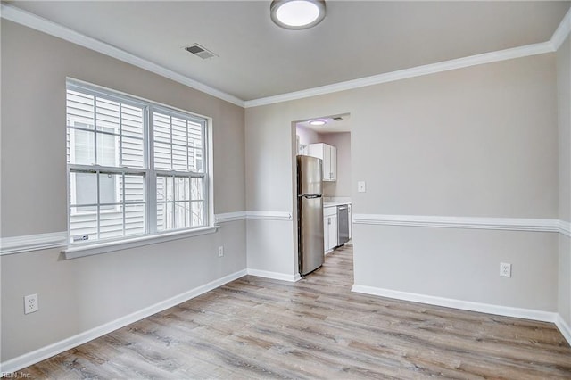 empty room featuring ornamental molding and light wood-type flooring