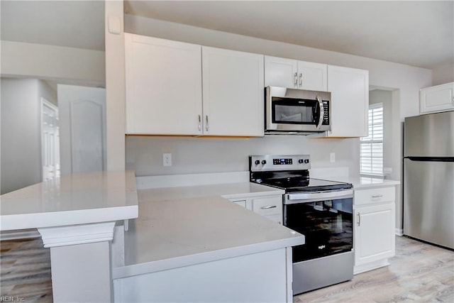 kitchen featuring appliances with stainless steel finishes, white cabinets, and light wood-type flooring