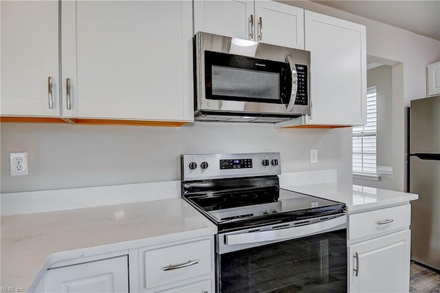 kitchen with appliances with stainless steel finishes, light stone countertops, and white cabinets