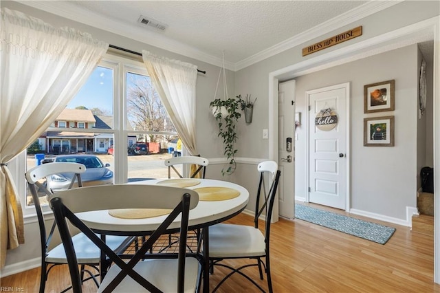 dining area with wood-type flooring, a textured ceiling, and crown molding