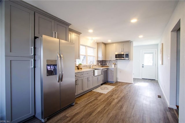 kitchen featuring sink, appliances with stainless steel finishes, gray cabinetry, dark hardwood / wood-style floors, and decorative backsplash