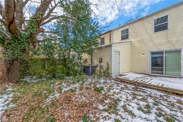 snow covered rear of property featuring central AC unit