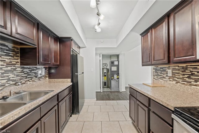 kitchen with stainless steel refrigerator, tasteful backsplash, sink, light tile patterned floors, and dark brown cabinets