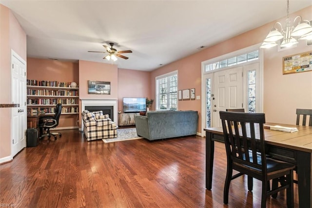 dining space with ceiling fan with notable chandelier and dark hardwood / wood-style flooring