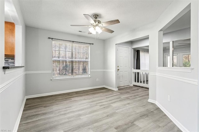 empty room featuring ceiling fan, plenty of natural light, and light hardwood / wood-style flooring