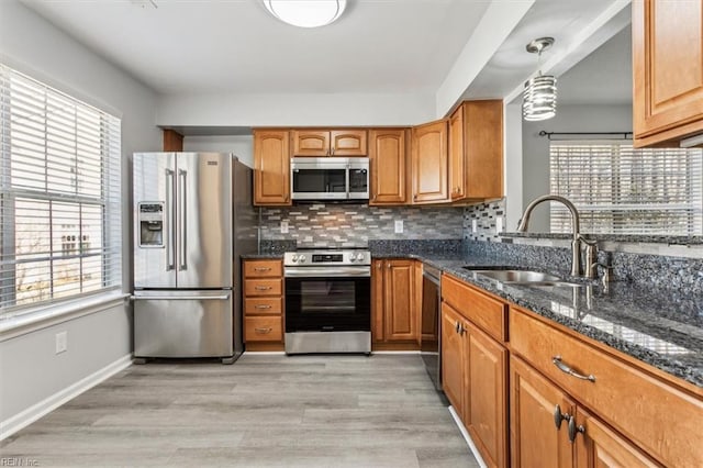 kitchen featuring sink, hanging light fixtures, stainless steel appliances, decorative backsplash, and dark stone counters