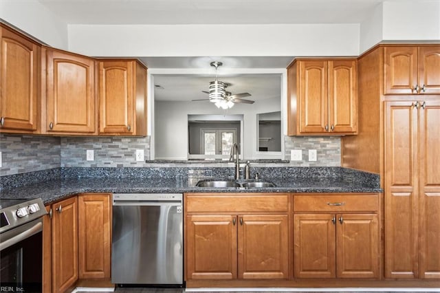 kitchen featuring appliances with stainless steel finishes, decorative light fixtures, sink, dark stone countertops, and backsplash