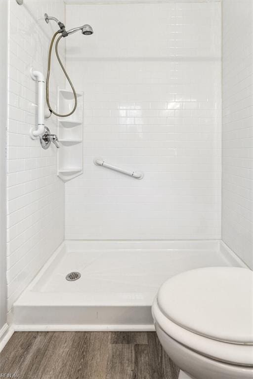 bathroom featuring tiled shower, wood-type flooring, and toilet