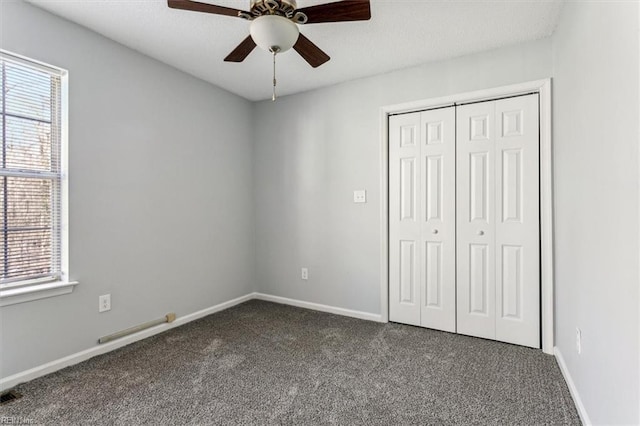 unfurnished bedroom with dark carpet, a closet, and ceiling fan