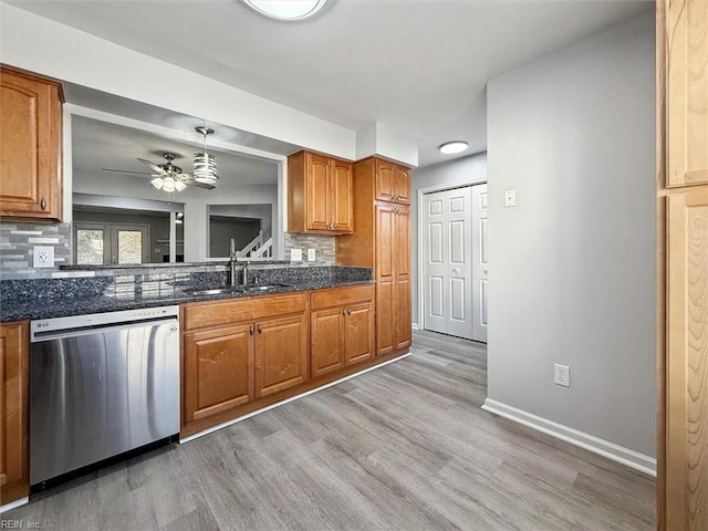 kitchen featuring sink, stainless steel dishwasher, dark stone counters, and decorative light fixtures