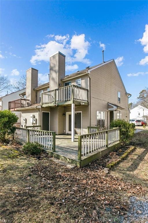 rear view of property featuring a balcony and a deck