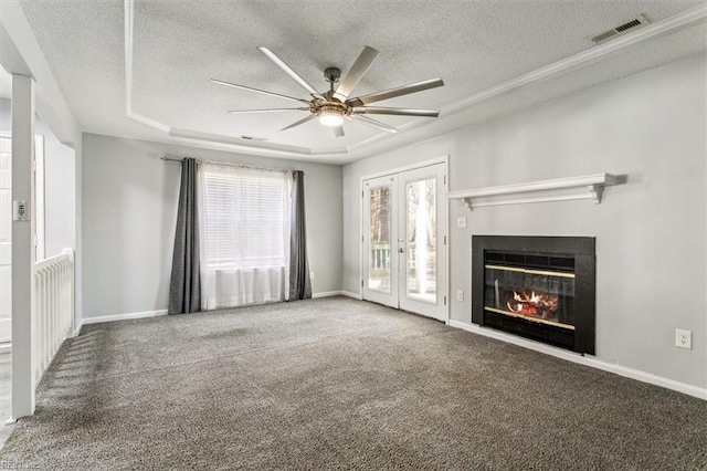 unfurnished living room featuring ceiling fan, a tray ceiling, a textured ceiling, and carpet